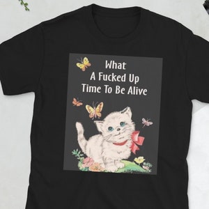 May include: Black t-shirt with a white kitten and butterflies. The text on the shirt reads "What A Fucked Up Time To Be Alive".