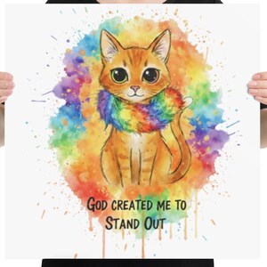 Puede incluir: Un póster cuadrado con una ilustración de acuarela de un gato naranja con una bufanda arcoíris. El gato está sobre un fondo colorido y salpicado. El texto "GOD CREATED ME TO STAND OUT" está impreso debajo.