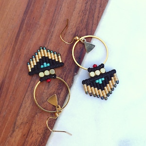 May include: A pair of gold hoop earrings with black and gold beaded fringe. The fringe features turquoise and red beads.
