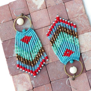May include: A pair of turquoise, red, and gold beaded dangle earrings with white bead accents and brass hoops.