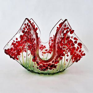 May include: A clear glass bowl with a red and green floral design. The bowl is shaped like a flower and has a wide opening. It is perfect for holding small items or flowers.