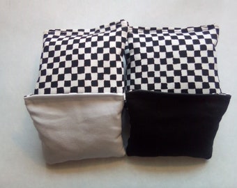 May include: Two black and white checkered bean bags with a black and white checkered fabric on the top and a solid black or white fabric on the bottom.