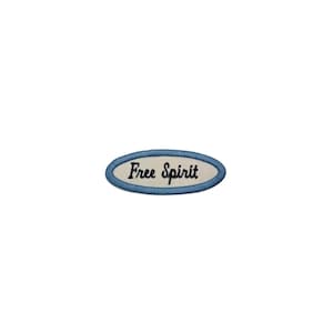 May include: Oval patch with the words "Free Spirit" embroidered in black script on an off-white background. The patch has a light blue border and is likely for clothing or accessories.