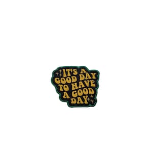 Pode incluir: Patch preto e verde com texto amarelo que diz "É um bom dia para ter um bom dia".