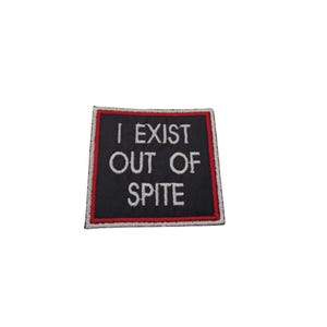 May include: Black embroidered patch with white text that reads "I EXIST OUT OF SPITE" surrounded by a red and white border.