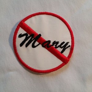 May include: A white circle with a red diagonal line through it. The word "Marry" is written in black cursive letters inside the circle.