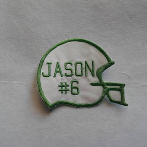 May include: Green and white embroidered patch of a football helmet with the name "JASON" and the number "#6" on it.