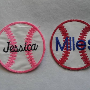May include: Two white baseball-shaped patches with pink and red stitching. The patches have the names "Jessica" and "Miles" embroidered on them in black and blue thread.