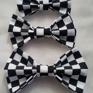 May include: Three black and white checkered bow ties of different sizes.
