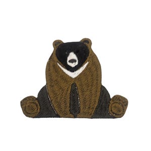 May include: A brown and black embroidered patch of a bear sitting down. The bear has a white patch on its chest.