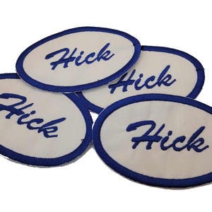 May include: Four white oval patches with blue embroidered borders. Each patch has the word "Hick" written in blue cursive.