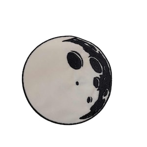 May include: A black and white embroidered patch of a crescent moon with craters.