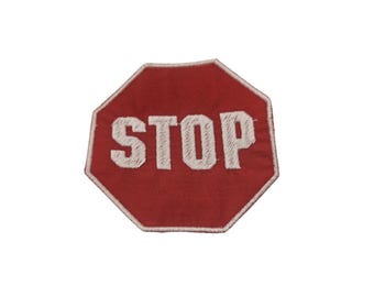 Könnte beinhalten: Ein rotes achteckiges Stoppschild mit weiß gesticktem Text, der "STOP" lautet.