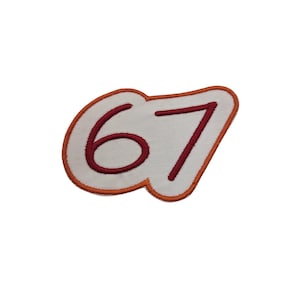 May include: Embroidered patch featuring the number "67" in a bold, red font. The number is set against a white background with a wavy, orange border. This patch is designed for application on clothing or accessories.
