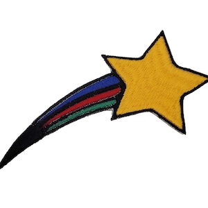 May include: A yellow star with a black outline and a rainbow-colored tail. The star is fuzzy and the tail is made of black, blue, red, and green fabric.