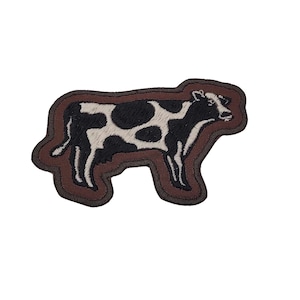 May include: A brown embroidered patch with a black and white cow design.