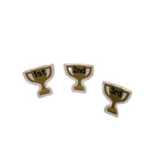 以下が含まれることがあります： 3つの刺繍されたトロフィーパッチ。各ゴールドカラーのトロフィーは白い縁取りがあり、「1st」、「2nd」、「3rd」の数字が黒で刺繍されています。 成果を祝うのに最適です。