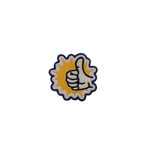 May include: A yellow and white embroidered patch with a thumbs up hand gesture in the center. The patch has a blue outline and a white background.