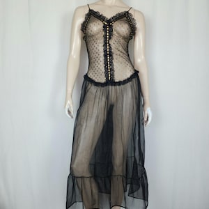 May include: A black sheer sleeveless dress featuring a polka dot pattern on the bodice, a vertical central panel with gold-toned accents, lace trim along the neckline, and a long, flowing skirt with a ruffled hemline at the bottom.