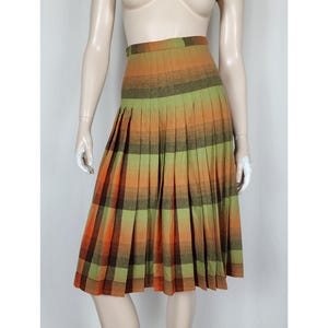 May include: A colourful pleated skirt in orange, green, and brown plaid. The skirt is displayed on a mannequin. The high-waisted skirt is made of a woven fabric. The skirt's length is approximately 60 cm.