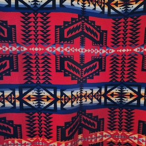 Peut inclure: Gros plan sur un textile rouge avec un motif géométrique. Le motif présente des formes répétitives en bleu marine, blanc, jaune et bleu. Le motif rappelle les motifs amérindiens.