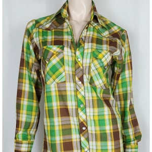 May include: A long-sleeved plaid shirt with a brown, green, yellow, and white plaid pattern. The shirt has a button-down collar and two chest pockets.