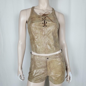 Peut inclure: Un ensemble deux pièces composé d'un haut sans manches et d'un short avec une finition dorée et beige à motif peau de serpent. Le haut présente un laçage frontal avec des cordons marron, tandis que le short inclut une fermeture à bouton.