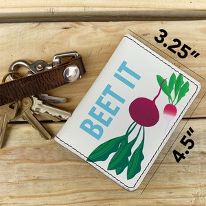 May include: White leather key chain with a beet illustration and the text "BEET IT" in blue. The key chain measures 4.5 inches by 3.25 inches.