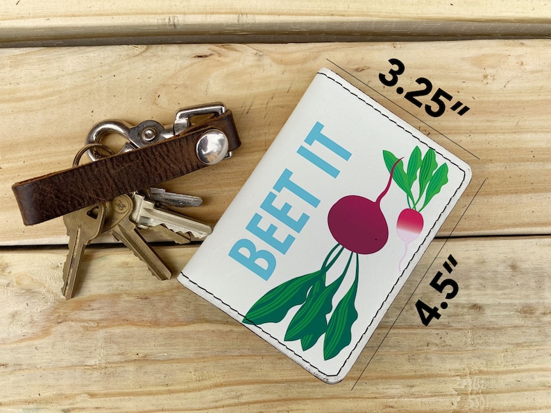 May include: White leather key chain with a beet illustration and the text "BEET IT" in blue. The key chain measures 4.5 inches by 3.25 inches.
