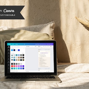 May include: A laptop computer open to a Canva design page with a list of items and a color palette. The laptop is on a bed with a white and green blanket.