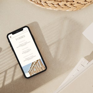 May include: A smartphone displaying a website with the word "TOURS" in a white font on a black background. The website lists different tours, including "ACROPOLIS", "SANTORINI", and "KNOSSOS PALACE". The image at the bottom of the screen shows a white marble structure with columns.