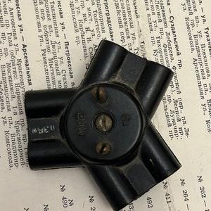 Puede incluir: Una caja de conexiones eléctricas de plástico negro con tres salidas. La caja tiene el texto "250V" impreso en ella.