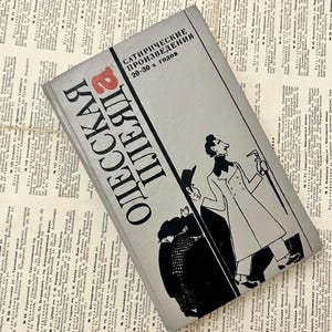Può includere: Un libro grigio con illustrazioni in bianco e nero di persone. Il titolo del libro è "ODESSKAYA PLEADA" e il sottotitolo è "SATIRICHESKIE PROIZVEDENIYA 20-30-kh godov".
