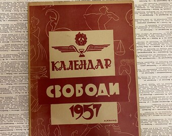 May include: A red and white calendar with the text "КАЛЕНДАРЬ СВОБОДЫ 1957" and a winged hourglass symbol. The calendar is decorated with zodiac symbols.