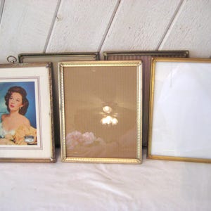 Puede incluir: Una colecci&oacute;n de marcos de fotos antiguos en varios tama&ntilde;os y estilos. Los marcos tienen acabados dorados y plateados, algunos con detalles ornamentados. Un marco contiene un anuncio vintage con una mujer. Los marcos est&aacute;n dispuestos sobre una superficie blanca.