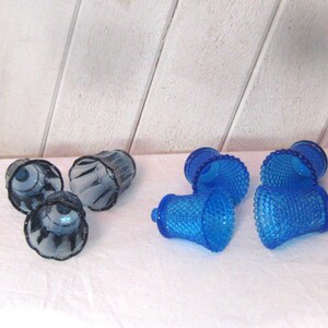 Könnte beinhalten: Satz mit sechs Kerzenhaltern aus Glas. Drei sind blau mit einer strukturierten Oberfläche und drei sind dunkelblau mit einer glatten Oberfläche.