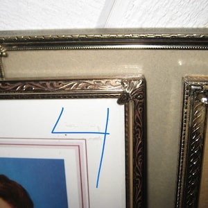 Puede incluir: Primer plano de marcos de fotos antiguos con detalles dorados ornamentados. Los marcos est&aacute;n dispuestos en una configuraci&oacute;n de m&uacute;ltiples marcos, mostrando una est&eacute;tica vintage. Los marcos tienen un paspart&uacute; beige y un fondo blanco.