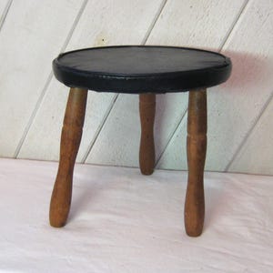 Antique wooden three leg foot stool, brown turn wood legs, black vinyl upholstered milking stool, rustic distressed, mid century 30s 40s