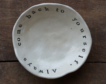 Small meditative dish imprinted with the words "Always come back to yourself" composed of white stoneware.