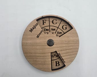 Puede incluir: Un círculo de madera con notas musicales y texto grabados, incluyendo "Major", "Minor" y "Diminished". Se muestran las notas F, C, G, B y otras. Un pequeño imán está en el centro.