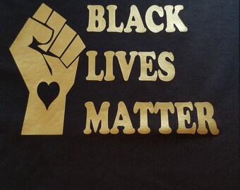 May include: Black t-shirt with a gold raised fist and the words "Black Lives Matter" in gold.