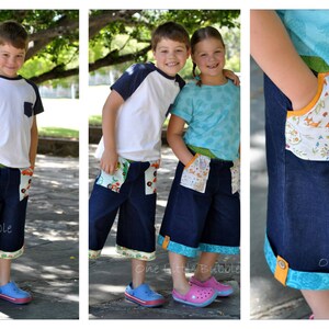 May include: Two children wearing denim shorts with colorful fabric trim and pockets. The boy is wearing a white and blue striped shirt and the girl is wearing a light blue shirt. Both children are smiling.