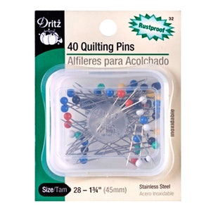 May include: A clear plastic container filled with 40 rustproof quilting pins. The pins are 1 3/4 inches long and are made of stainless steel. The container is labeled "Dritz 40 Quilting Pins" and "Alfileres para Acolchado".