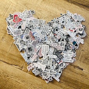 Könnte beinhalten: Eine herzförmige Anordnung von Aufklebern mit verschiedenen Zitaten und Illustrationen zum Thema Bücher. Die Aufkleber zeigen Sätze wie "Book Nerd" und "Book Lover". Die Farbpalette umfasst Schwarz, Weiß und Rot.