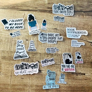 K&ouml;nnte beinhalten: Eine Sammlung von Buch-Sticker mit verschiedenen Designs und Spr&uuml;chen. Einige Sticker zeigen Illustrationen von B&uuml;chern, w&auml;hrend andere Text wie "Ich habe mein Buch geschlossen, um hier zu sein", "B&uuml;cher sind g&uuml;nstiger als Therapie" und "Du hattest mich bei der Warnung!" enthalten.