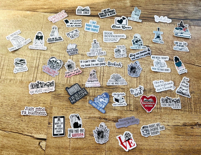 K&ouml;nnte beinhalten: Eine Sammlung von Buch-Stickern mit verschiedenen Zitaten und Illustrationen. Die Sticker sind in Schwarzwei&szlig; gedruckt, einige mit roten Akzenten. Die Sticker sind auf einer Holzoberfl&auml;che angeordnet.