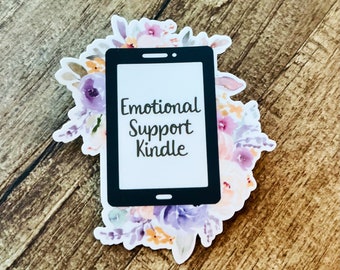 May include: A black and white sticker of a smartphone with the text "Emotional Support Kindle" surrounded by purple, pink, and orange watercolor flowers.