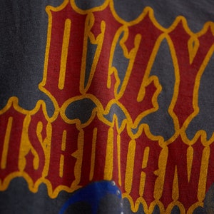 Puede incluir: Una camiseta gris oscuro con las palabras "Ugly" e "Is" impresas en rojo y amarillo.