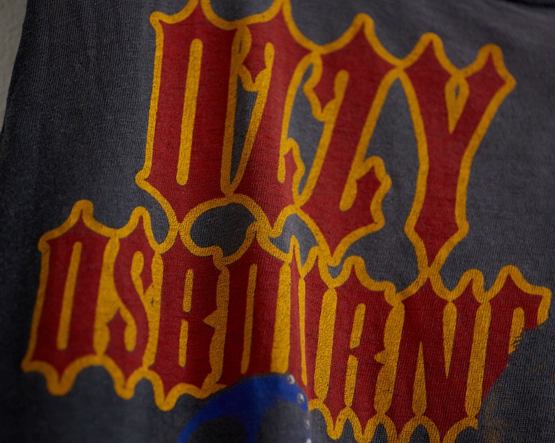 Puede incluir: Una camiseta gris oscuro con las palabras "Ugly" e "Is" impresas en rojo y amarillo.