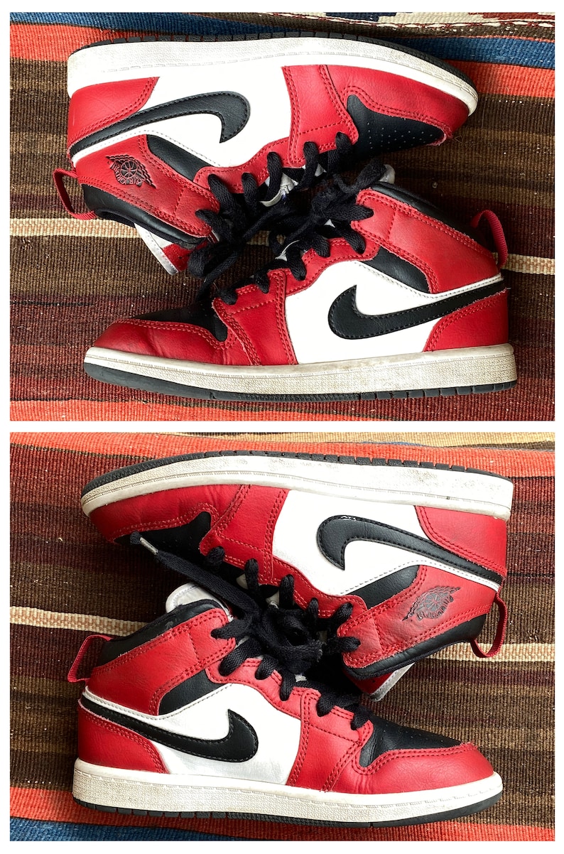 May include: A pair of red, white, and black sneakers with a black swoosh logo. The sneakers have a white midsole and a black outsole.